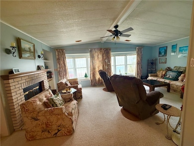 Living area with carpet flooring, a fireplace, and a ceiling fan