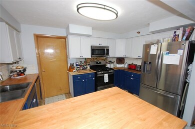 Kitchen with white cabinetry, appliances with stainless steel finishes, tasteful backsplash, blue cabinets, and a textured ceiling