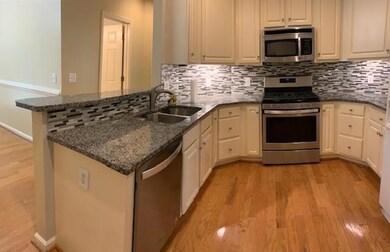 Kitchen with stainless steel appliances, dark stone countertops, and light wood-style flooring