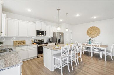 Kitchen with stainless steel appliances, a center island, white cabinetry, light wood finished floors, and recessed lighting
