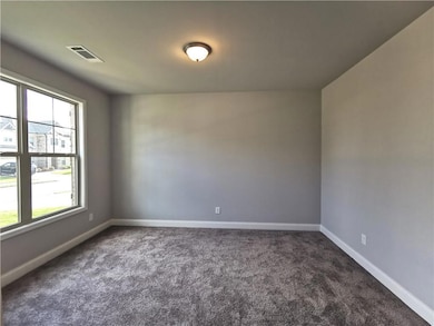 Empty room featuring dark colored carpet and baseboards