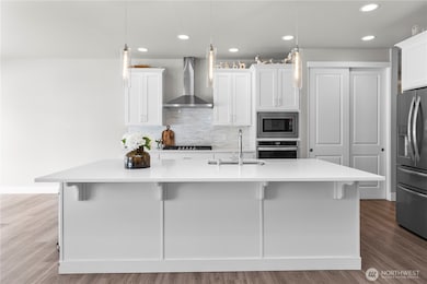 Beautiful open concept kitchen with large island and modern hood with gas stove, furnished with white cabinetry.