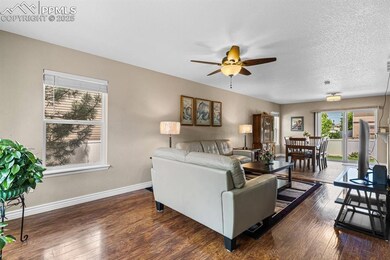 Living area featuring ceiling fan, baseboards, and wood-type flooring