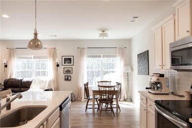 Kitchen with stainless steel appliances, a sink, light wood-type flooring, tasteful backsplash, and pendant lighting