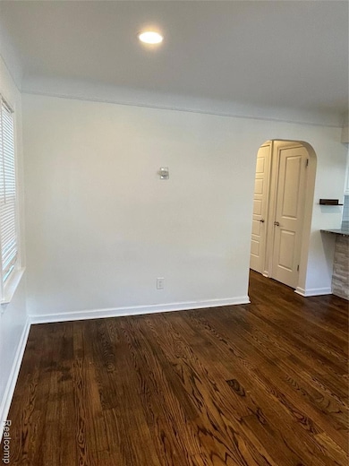 Spare room featuring arched walkways, dark wood finished floors, and recessed lighting