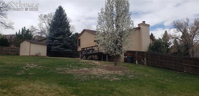 View of yard with a deck, a fenced backyard, an outdoor structure, and a storage unit