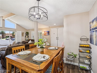 Dining space with dark wood-style floors, a textured ceiling, healthy amount of natural light, and a chandelier