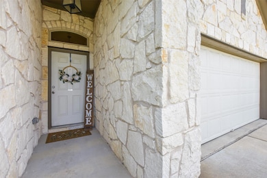Property entrance with stone siding and a garage