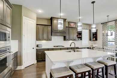 Chef's kitchen is a dream- stainless steel appliances, large island with beautiful white marble counters, modern white subway tile backsplash, and unique pendant lighting.