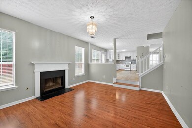 Unfurnished living room featuring light wood finished floors, a textured ceiling, a fireplace with raised hearth, stairs, and a chandelier