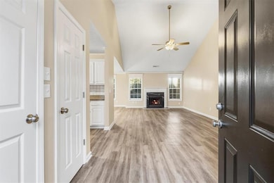 Unfurnished living room with light wood-type flooring, a premium fireplace, a ceiling fan, and high vaulted ceiling