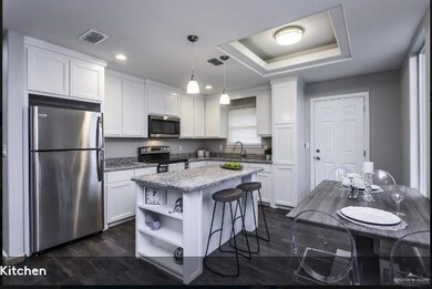 Kitchen with stainless steel appliances, white cabinets, open shelves, a center island, and a raised ceiling