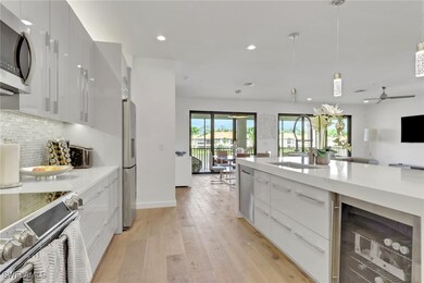 Kitchen with modern cabinets, wine cooler, hanging light fixtures, white cabinetry, and stainless steel appliances
