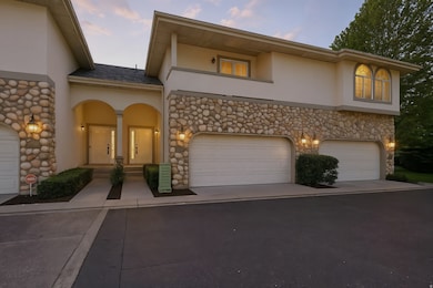 View of front of property with stucco siding, stone siding, driveway, a garage, and covered porch