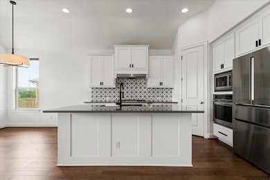 Kitchen with white cabinets, dark countertops, wa