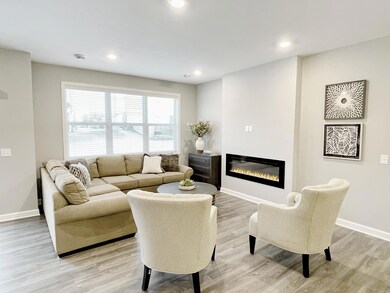The home is covered in natural light and the hard surface flooring (LVP) is continued in the family room. The focal point of the family room is the centered electric fireplace. Photo of similar home, colors and finishes will vary.