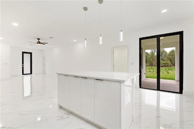Kitchen featuring light marble finish floors, white cabinets, modern cabinets, hanging light fixtures, and recessed lighting
