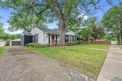 Single story home featuring an outdoor structure, a front lawn, a garage, roof with shingles, and covered porch