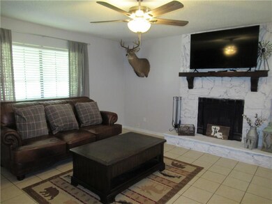 Den with tile flooring, ceiling fan, & wood burnin