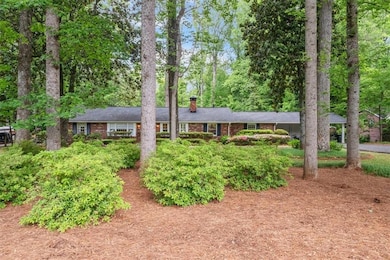 Single story home with a chimney and brick siding