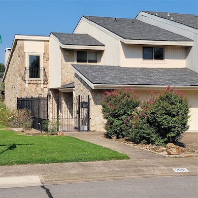 View of front facade featuring a garage, stone siding, and roof with shingles