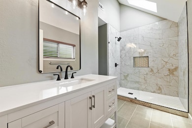 Bathroom with walk in shower, vanity, a skylight,