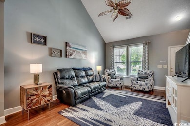 Living area with a ceiling fan, wood finished floors, and high vaulted ceiling