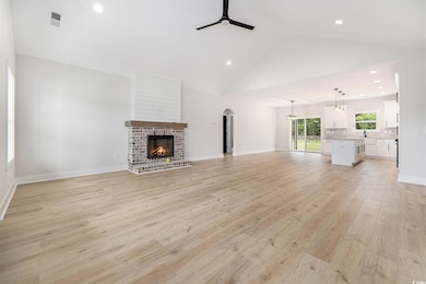 Unfurnished living room featuring a ceiling fan, a fireplace, recessed lighting, light wood-type flooring, and high vaulted ceiling