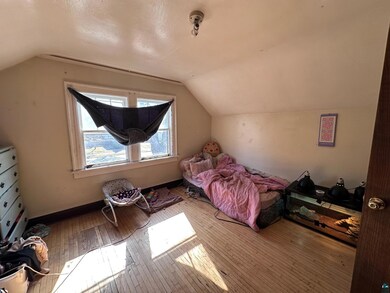 Bedroom with baseboards, vaulted ceiling, and hard
