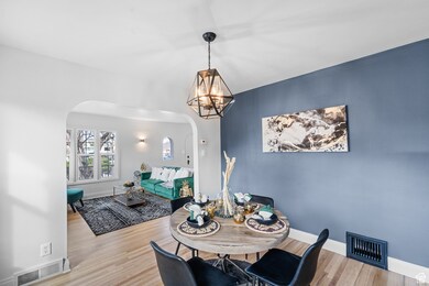 Dining room featuring arched walkways, light wood-type flooring, and a chandelier