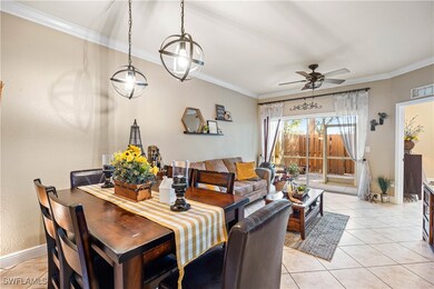 Tiled dining space with ceiling fan and crown mold