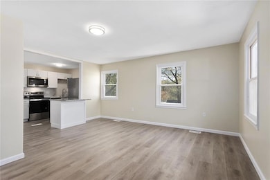 Unfurnished living room featuring light wood-type flooring and plenty of natural light