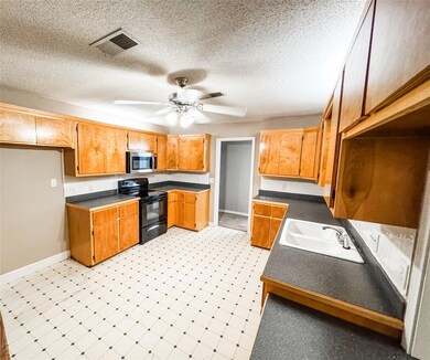 Kitchen with ceiling fan, a textured ceiling, black / electric stove, and sink