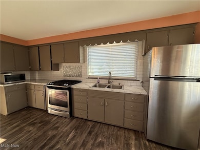 Kitchen with appliances with stainless steel finishes, light countertops, tasteful backsplash, and gray cabinets