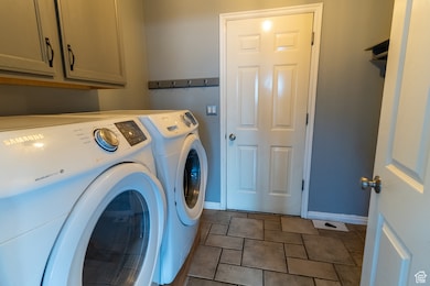 Laundry area with washer and clothes dryer, cabinet space, and tile patterned flooring