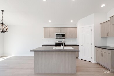 Kitchen featuring light brown cabinets, a kitchen island with sink, stainless steel appliances, recessed lighting, and decorative light fixtures
