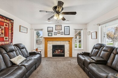 Carpeted living area with a tile fireplace and a ceiling fan