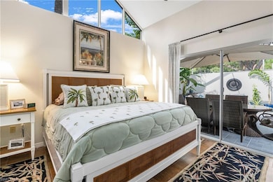 Bedroom featuring access to outside, wood finished floors, high vaulted ceiling, and a sunroom