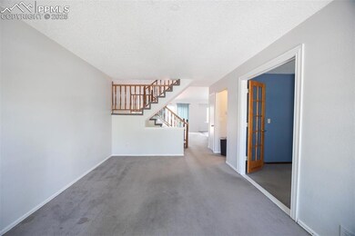 Spare room with carpet floors, stairway, a textured ceiling, and baseboards