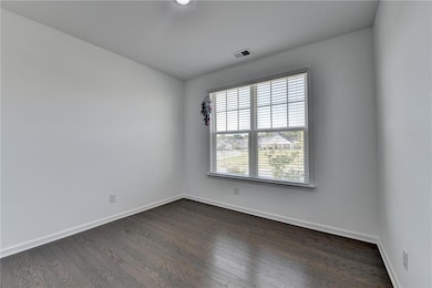 Empty room featuring dark wood-style flooring, vis