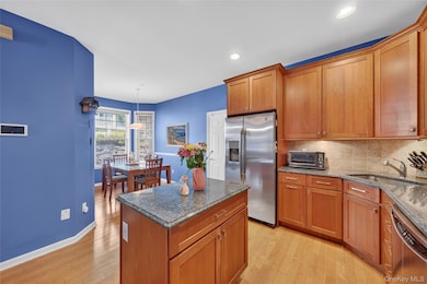 Kitchen featuring stainless steel appliances, backsplash, wood floors, cabinets, and granite countertops