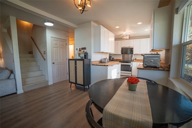 Kitchen featuring updated soft close white cabinetry, Pergo flooring, new electric range, updated butcher block counters, and recessed lighting with changeable light colors.