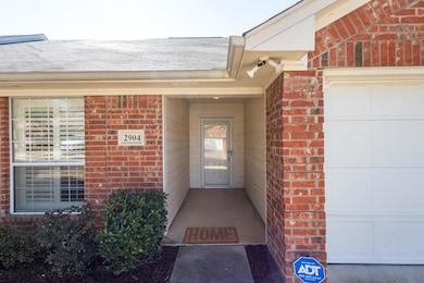 Doorway to property featuring a garage, brick sidi