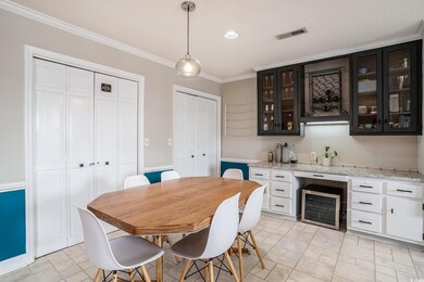Dining space featuring wine cooler, crown molding, bar with sink, and recessed lighting