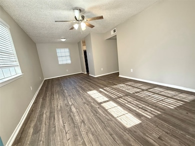 Empty room featuring dark wood-style flooring, a textured ceiling, and ceiling fan