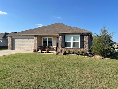 View of front of property featuring driveway, professional landscaping, brick siding, a shingled roof, and a covered porch