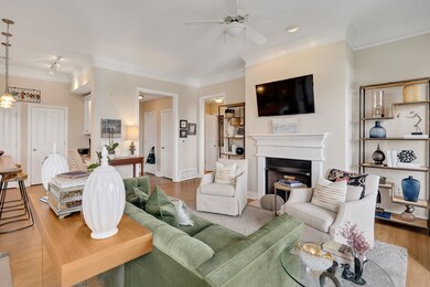 Living room featuring crown molding, a ceiling fan, wood finished floors, a fireplace, and a chandelier