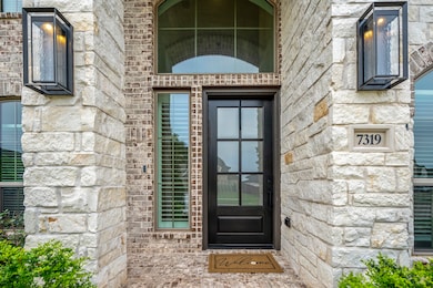Approaching the front door you see the details of the elegant brick and stone exterior. This spacious front porch is complete with a stained 8ft mahogany door, modern LED sconces, and a brick paved porch.