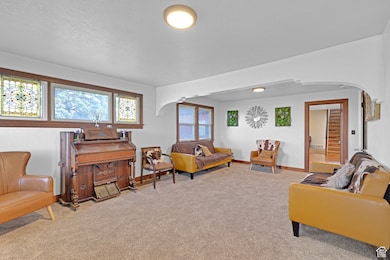 Carpeted living room featuring arched walkways and baseboards