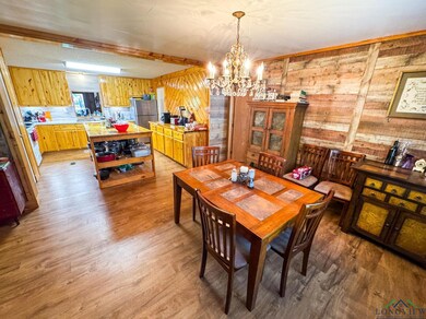 Dining area with light wood-style flooring, a chandelier, and wooden walls